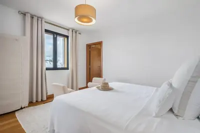 a white bedroom with a white bed and a window at Villa Piedade by Homie in Canhas