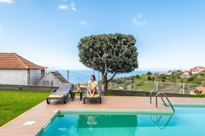 a woman sitting in a chair next to a swimming pool at Villa Piedade by Homie in Canhas