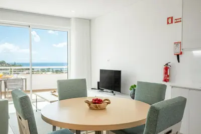 a dining room with a table and chairs with a view of the ocean at Green Beach Ocean View, Porto de Mós VR13 in Lagos