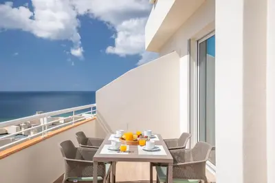 a table on a balcony with a view of the ocean at Green Beach Ocean View, Porto de Mós VR13 in Lagos