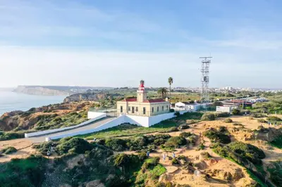 a building on a hill with a lighthouse on it at Green Beach Ocean View, Porto de Mós VR13 in Lagos