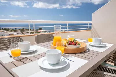 a table on a balcony with a tray of orange juice at Green Beach Ocean View, Porto de Mós VR13 in Lagos