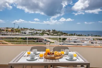 a table with a plate of food on a balcony at Green Beach Ocean View, Porto de Mós VR13 in Lagos