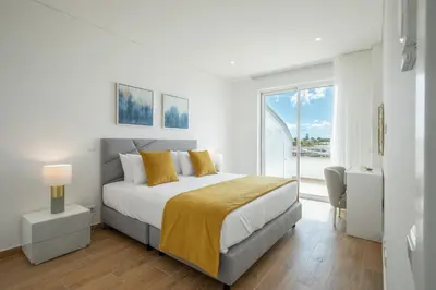 a white bedroom with a bed and a large window at Green Beach Ocean View, Porto de Mós VR13 in Lagos