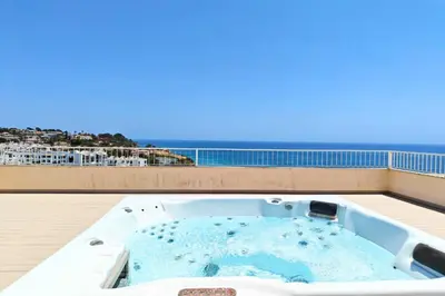 a hot tub on a balcony with the ocean in the background at Home By The Sea Ocean View Apartment in Lagos