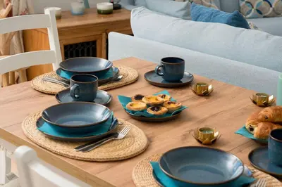 a wooden table with plates and cups and pastries on it at Shabby Chique Surf Beach and Ocean in Luz