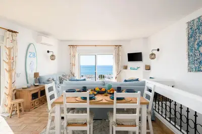 a living room with a table and a blue couch at Shabby Chique Surf Beach and Ocean in Luz