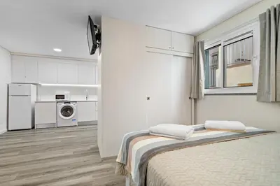 a white room with a bed and a kitchen at Studio Carmo in Funchal