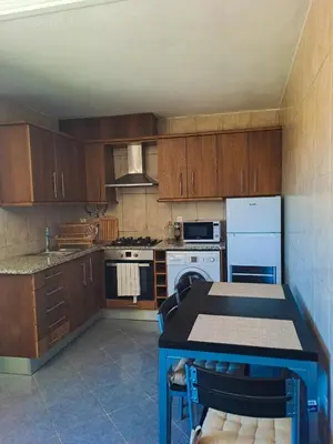 a kitchen with wooden cabinets and a table and a stove at Brisas da Raposeira in Raposeira