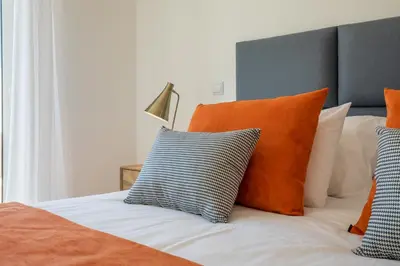 a bed with orange and white pillows and a lamp at Orange Beach Ocean View, Porto de Mós VR29 in Lagos