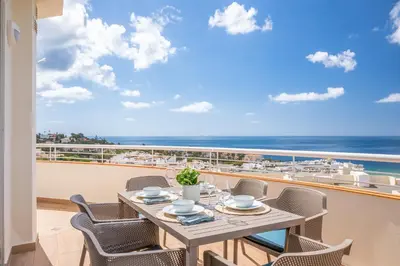 a table and chairs on a balcony with a view of the ocean at Blue Beach Ocean View, Porto de Mós VR14 in Lagos