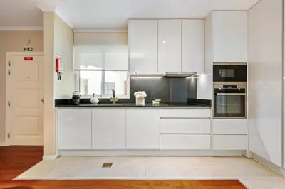 a white kitchen with white cabinets and appliances at Exquisite Ocean Apartment by Homie in Caniço