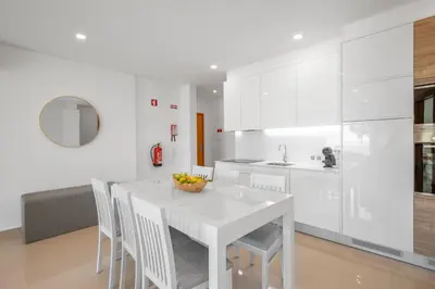 a white kitchen with a white table and chairs at Yellow Beach Ocean View, Porto de Mós VR38 in Lagos
