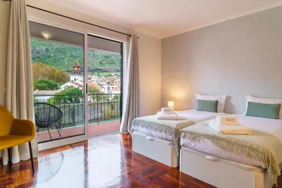 a bedroom with two beds and a large window at GuestReady - Peaceful getaway near the beach in Machico