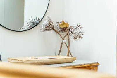 a table with a mirror and a vase with flowers at GuestReady - Peaceful getaway near the beach in Machico