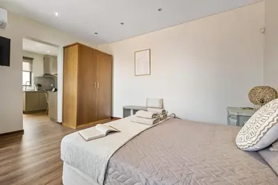 a bedroom with a large bed and a kitchen at Cozy Apartments by Homie in Porto Moniz