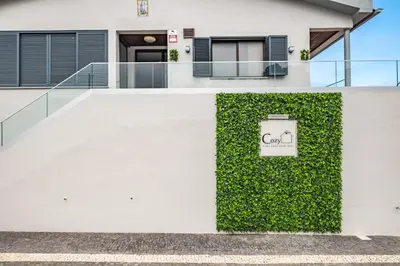 a white house with a green hedge at Cozy Apartments by Homie in Porto Moniz