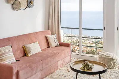 a pink couch in a living room with a large window at Skyline Heights by Homie in Funchal