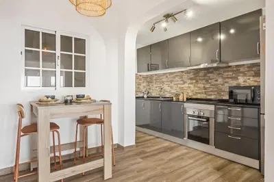 a kitchen with gray cabinets and a table with stools at Skyline Heights by Homie in Funchal