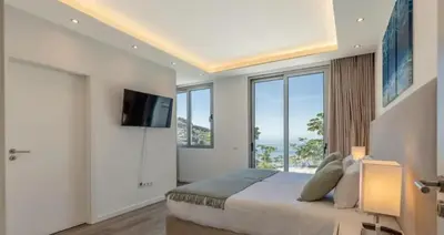 a bedroom with a large bed with a tv and windows at Villa Althea by YMR in Calheta