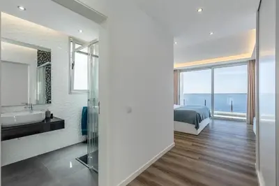 a bedroom with a bed and a bathroom with a sink at Villa Althea by YMR in Calheta