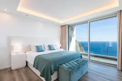a bedroom with a bed and a large window at Villa Althea by YMR in Calheta