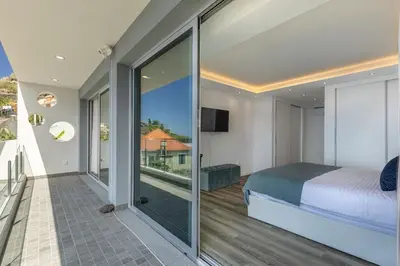 a bedroom with a bed and a balcony with a view at Villa Althea by YMR in Calheta