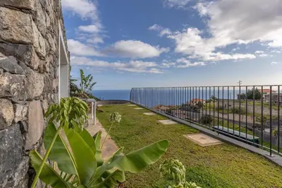 a dining room and living room with a table and chairs at Terraços da Calheta by YMR in Estreito da Calheta