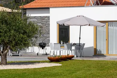 a white house with a table and chairs at OurMadeira - Chalet Prazeres in Prazeres
