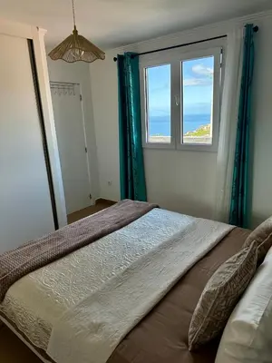 a bedroom with a bed with a window at Little Blue Paradise in Ribeira Brava