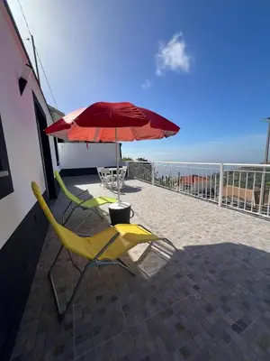 a table and a yellow chair under an umbrella at Little Blue Paradise in Ribeira Brava