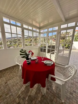 a dining room with a red table and chairs and windows at Little Blue Paradise in Ribeira Brava