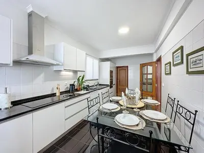 a kitchen with white cabinets and a table with plates on it at Ocean View Botânico in Funchal