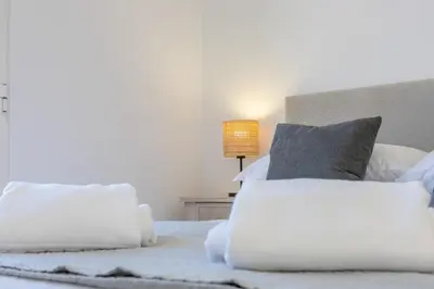 a bedroom with a white bed with pillows and a lamp at Funchal pad with Harbor Views & cool Aircon Bliss in Funchal