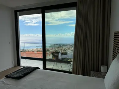 a bedroom with a large window with a view of the ocean at Bela Vista Funchal Villa in Funchal