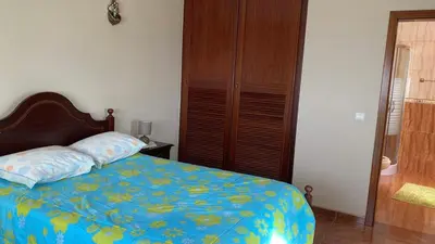 a bedroom with a bed with a blue comforter at La terraza de Ponta do Sol -Suite 1 in Ponta do Sol