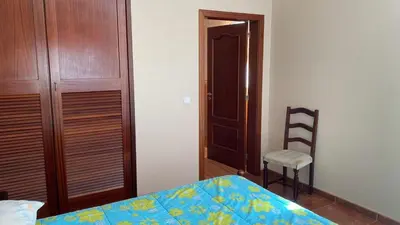a bedroom with a bed and a chair and a closet at La terraza de Ponta do Sol -Suite 1 in Ponta do Sol