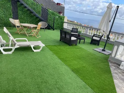 a green lawn with chairs and a table on a balcony at La terraza de Ponta do Sol -Suite 1 in Ponta do Sol