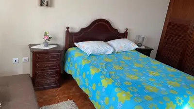 a bedroom with a bed with a blue comforter and a night stand at La terraza de Ponta do Sol -Suite 1 in Ponta do Sol