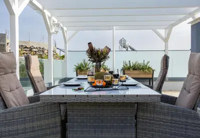 a dining table and chairs on a balcony at night at VILLA HELENA Crystal Apartment in Caniço