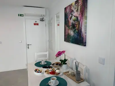 a kitchen with white cabinets and a blue couch at VILLA HELENA Crystal Apartment in Caniço