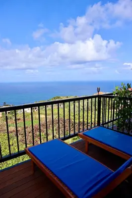 a balcony with two blue benches and the ocean at Faria's House 2 in Feiteiras