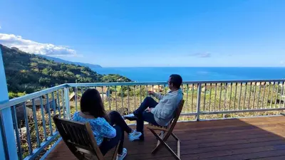 a man and woman sitting on chairs on a balcony at Faria's House 2 in Feiteiras