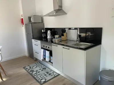 a white kitchen with a stove and a refrigerator at CGD São Vicente Apartments in São Vicente