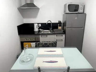 a small kitchen with a table and a refrigerator at CGD São Vicente Apartments in São Vicente