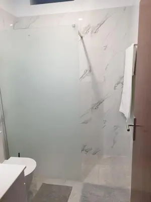 a white bathroom with a shower and a toilet at Silva House in Ribeira Brava