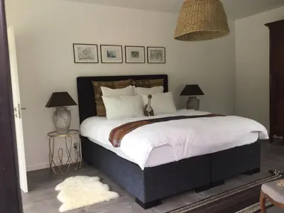 a bedroom with a large bed with two lamps and a rug at Tabua Lodge in Ponta do Sol