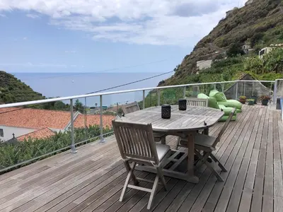 a wooden deck with a table and chairs on a balcony at Tabua Lodge in Ponta do Sol