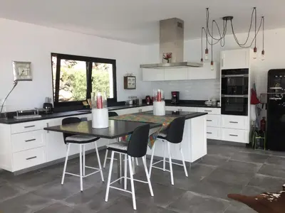 a kitchen with white cabinets and a table and chairs at Tabua Lodge in Ponta do Sol