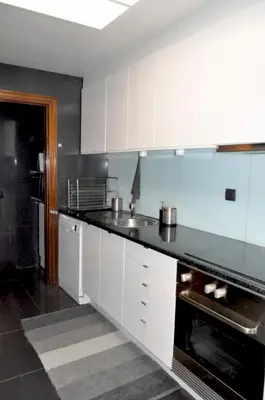 a kitchen with white cabinets and a black counter top at Refúgio Guest House in São Vicente